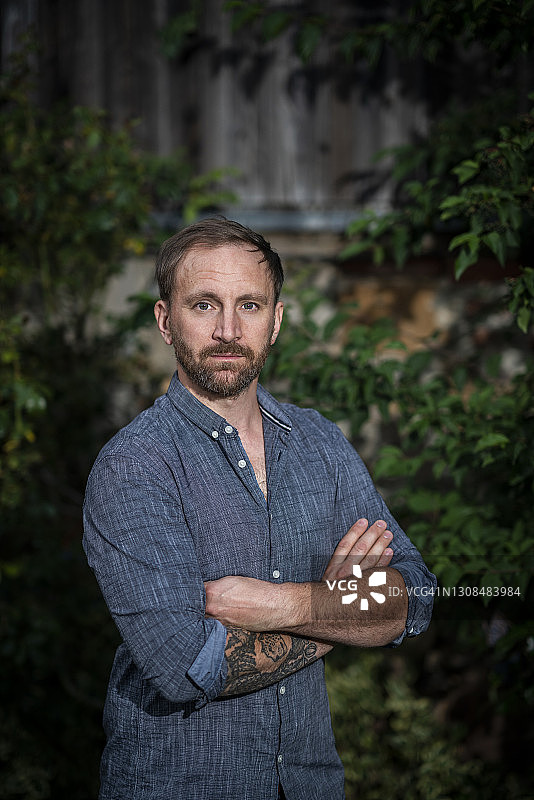 在花园里双手交叉站立的络腮胡男人图片素材