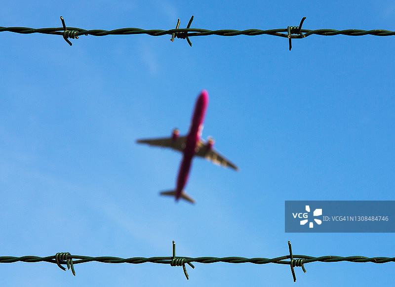 带刺铁丝网上空的客机图片素材