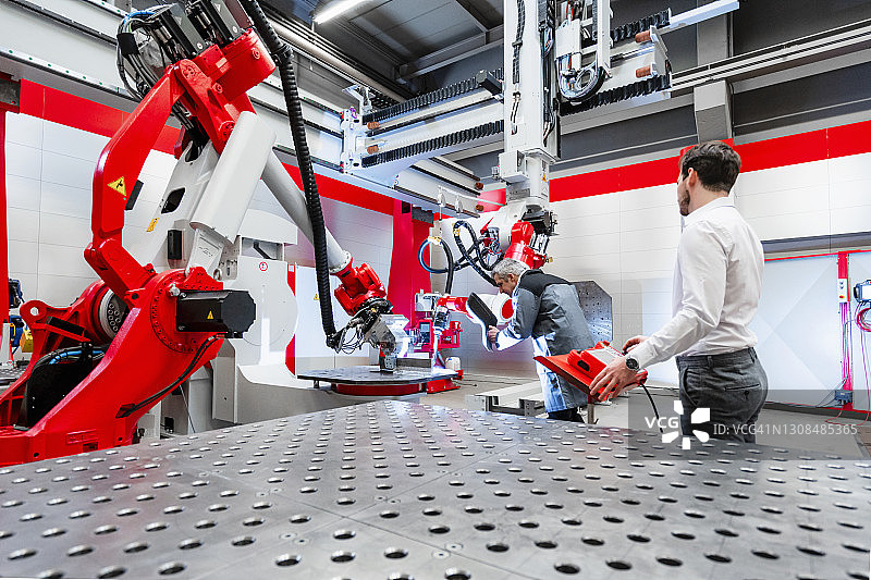 在工厂机械上工作的带焊接面罩的焊接工人图片素材