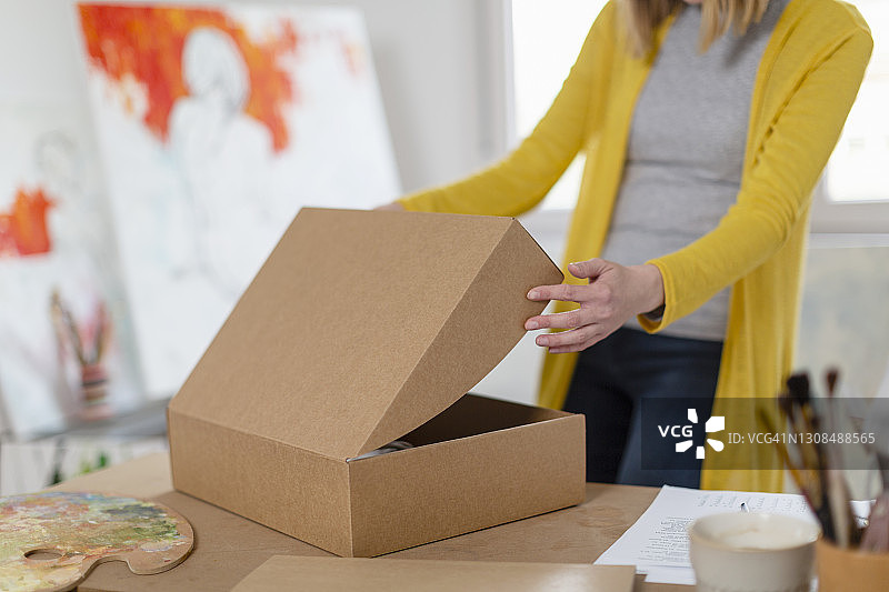 女人在家中工作室打开纸板箱图片素材
