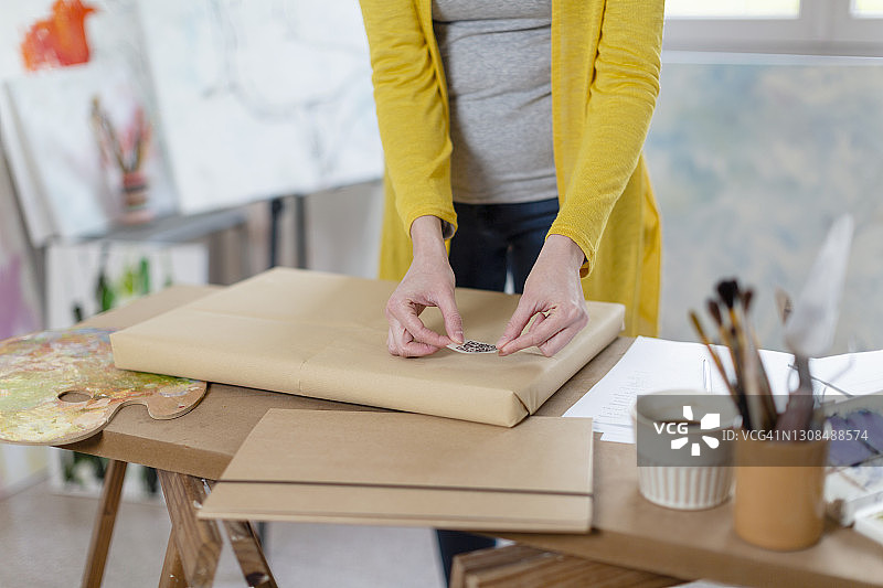 女人在家里的工作室里在快递包裹上贴条形码图片素材