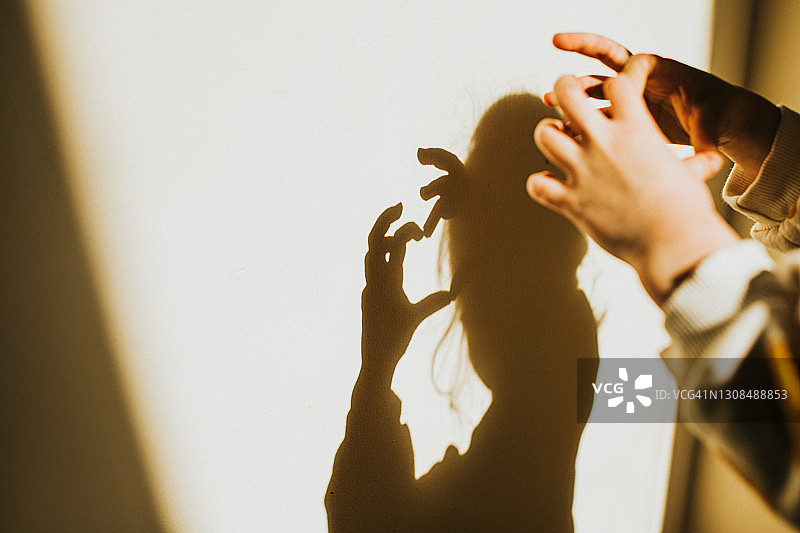 儿童用手指在白墙上创造影子图片素材