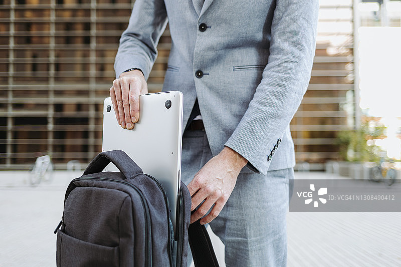 从背包里拿出笔记本电脑的商人图片素材