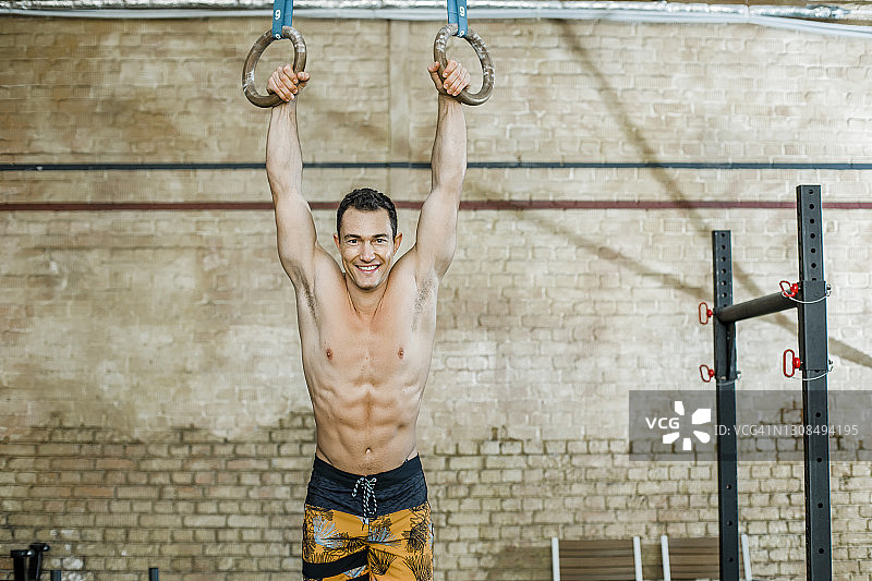 微笑的运动员在健身俱乐部手持吊环图片素材
