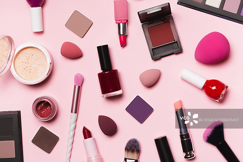 俯视粉色、浅蓝色和黄色背景上的化妆品套装。软刷、口红、粉饼、腮红、海绵、眼影和指甲油。扁平风格。使用明亮的装饰化妆品和美容产品图片素材
