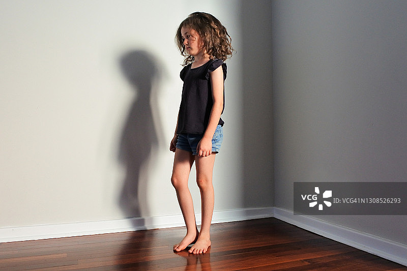 悲伤的女孩独自站在空房间的角落里图片素材