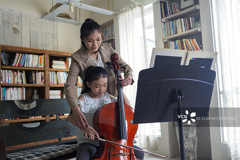 小女孩和音乐老师一起上大提琴课图片素材