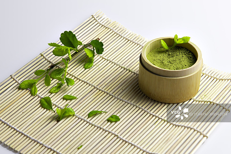 白色背景上的竹制杯装日本绿茶与茶叶图片素材