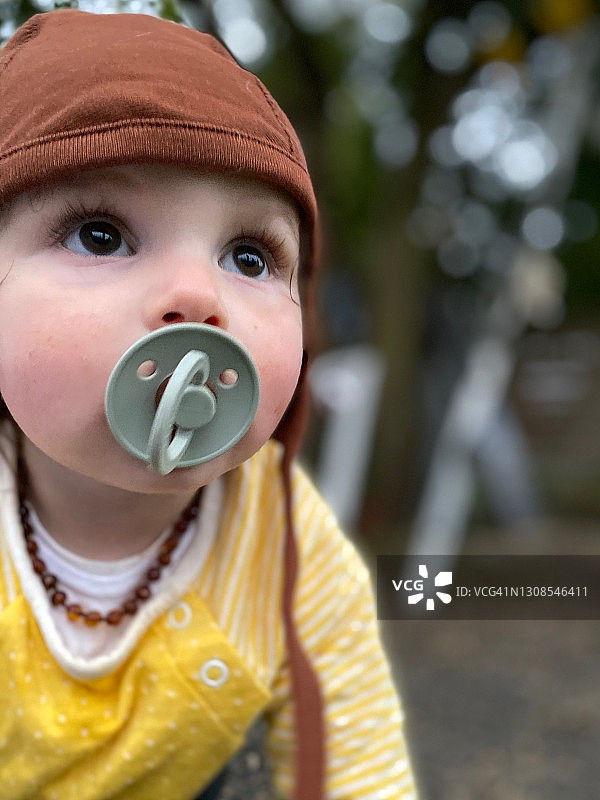 戴着紧身帽和琥珀项链爬行的婴儿图片素材