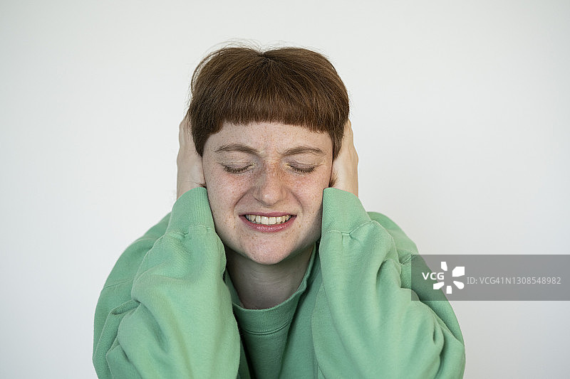 闭着眼睛用手捂住耳朵的压力女人特写图片素材