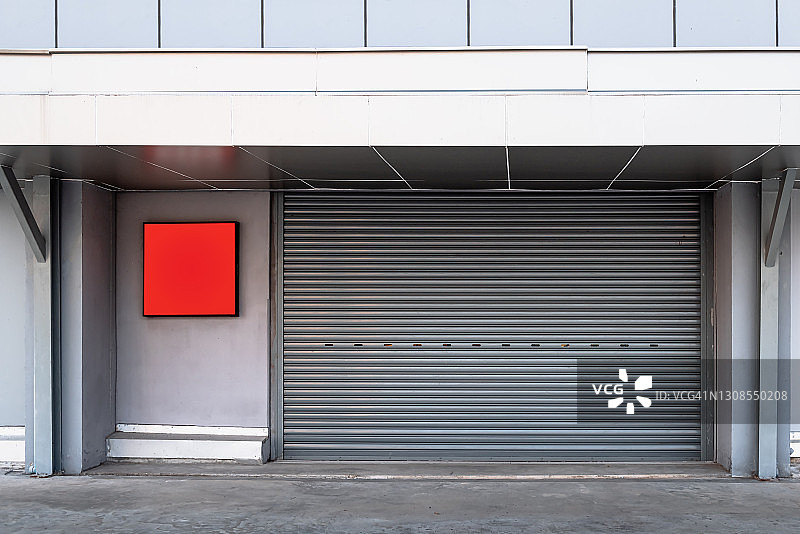 工厂仓库车间的钢制卷帘门，用于材料存储，卷帘金属门的前视图，用于访问和安全。仓库的门楼结构图片素材