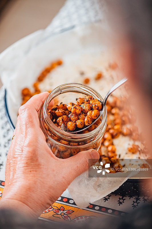 她将准备好的香辣鹰嘴豆倒入罐中图片素材
