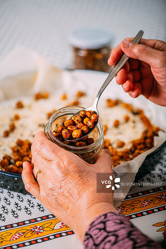 她将准备好的香辣鹰嘴豆倒入罐中图片素材