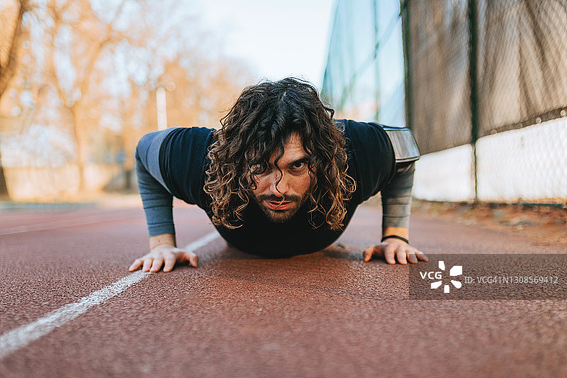 运动型卷发帅哥做俯卧撑图片素材