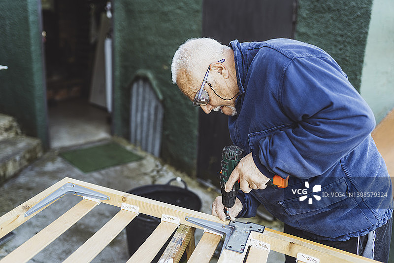 在花园里使用钻头的男人图片素材