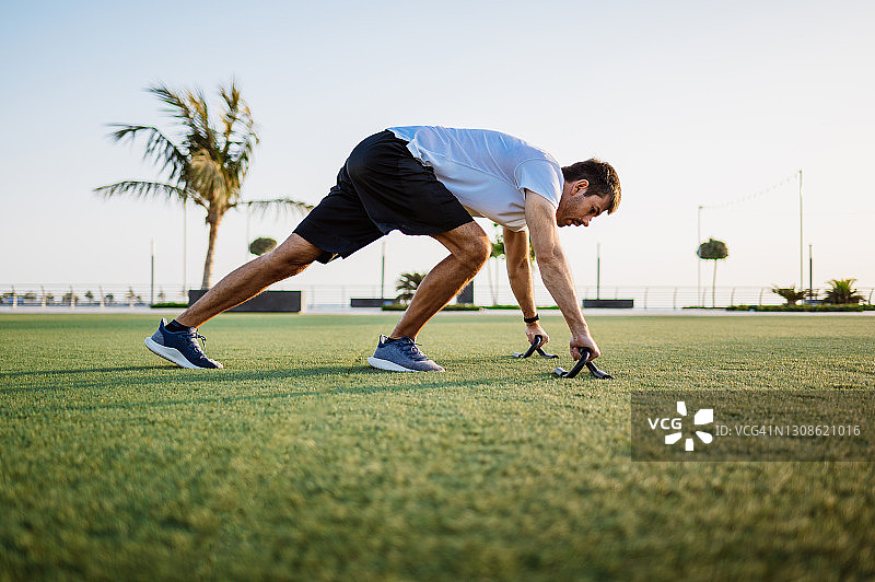 男人在公园草地上日落时做俯卧撑图片素材