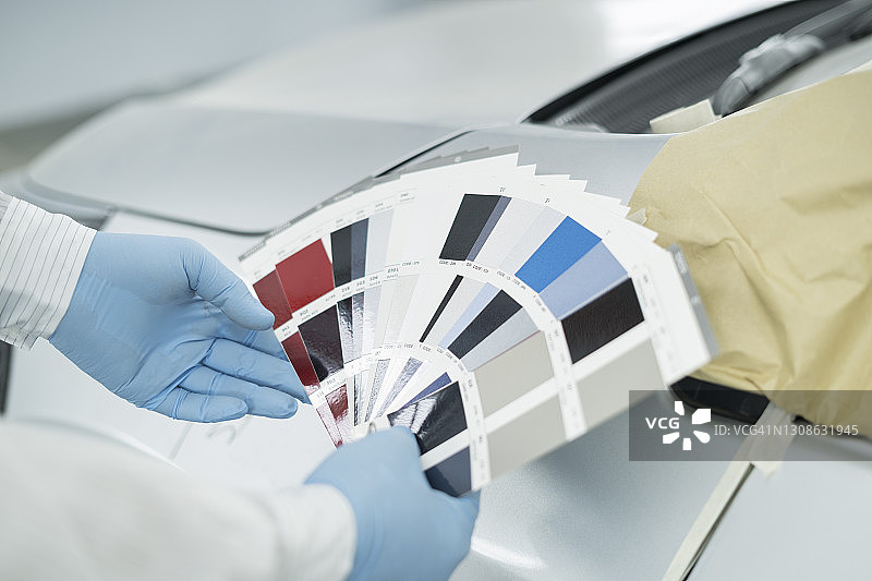 技术人员在喷漆室使用颜色样本匹配汽车颜色的裁剪图像图片素材
