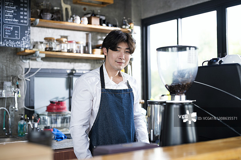 咖啡店吧台旁的男性咖啡师肖像，小企业主餐饮服务概念图片素材