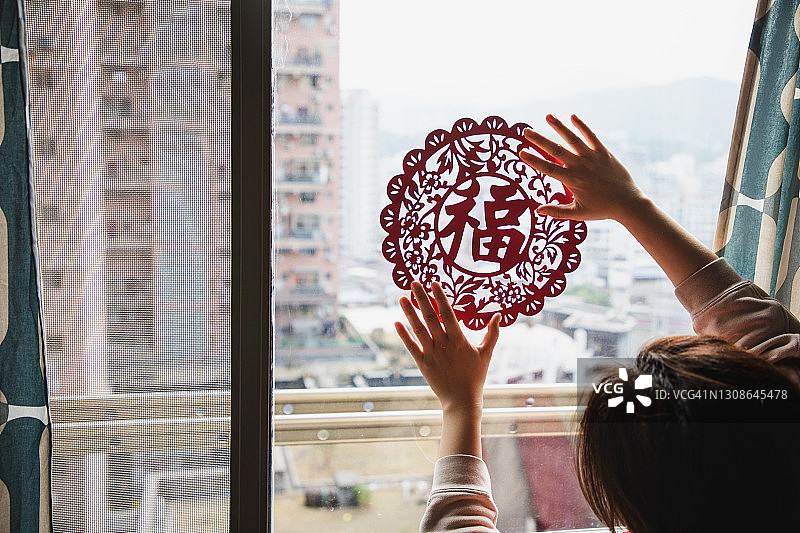 亚洲女性在家中悬挂中国新年装饰“福”字图片素材