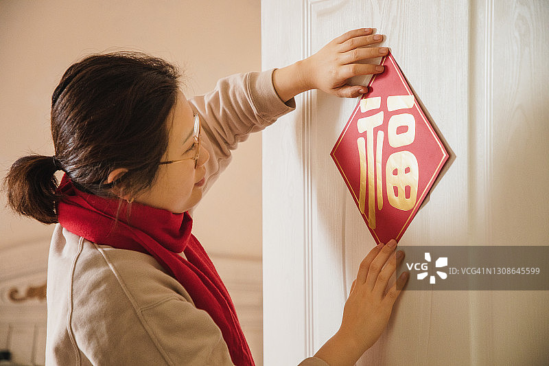 亚洲女性在家中悬挂中国新年装饰“福”字图片素材