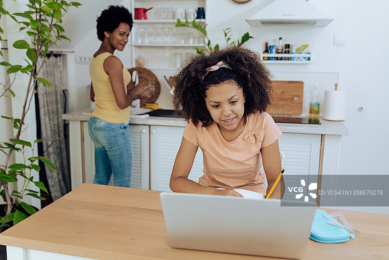 母亲在厨房工作，女儿在做作业图片素材