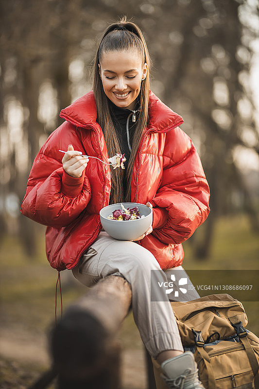 女徒步者在日出山顶休息并吃沙拉图片素材