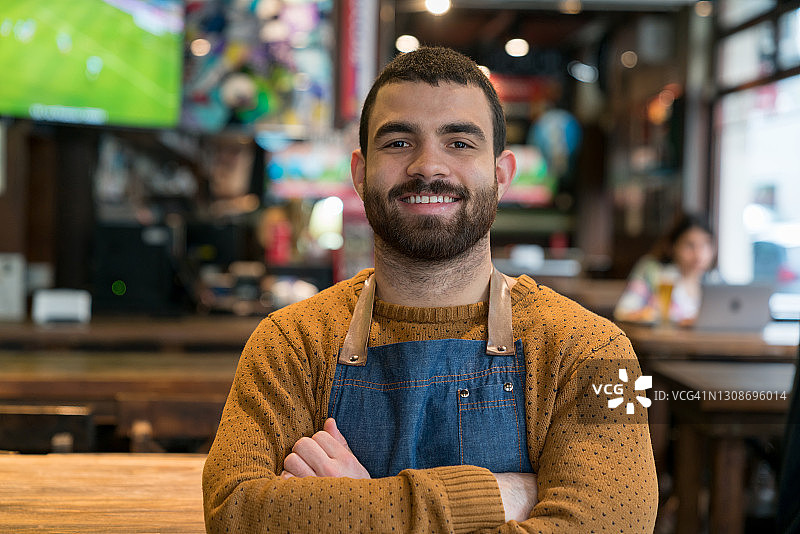 面带微笑、双臂交叉的酒吧老板肖像图片素材