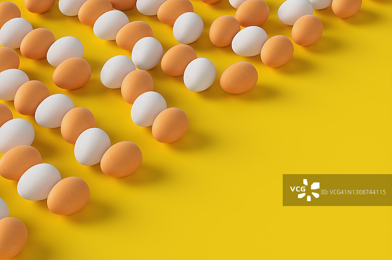 黄色背景上成排排列的棕色和白色生鸡蛋 3D渲染插图图片素材