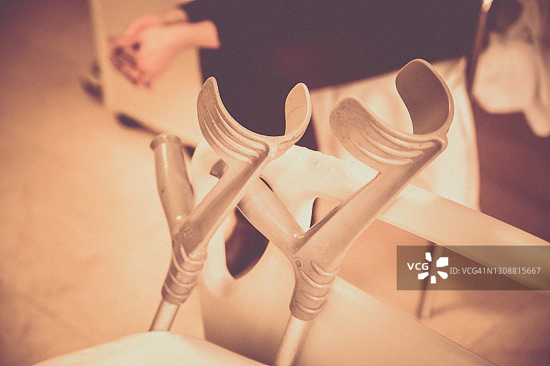 医院病房里靠在床上的两根拐杖，背景中坐着一位无法辨认的女人图片素材