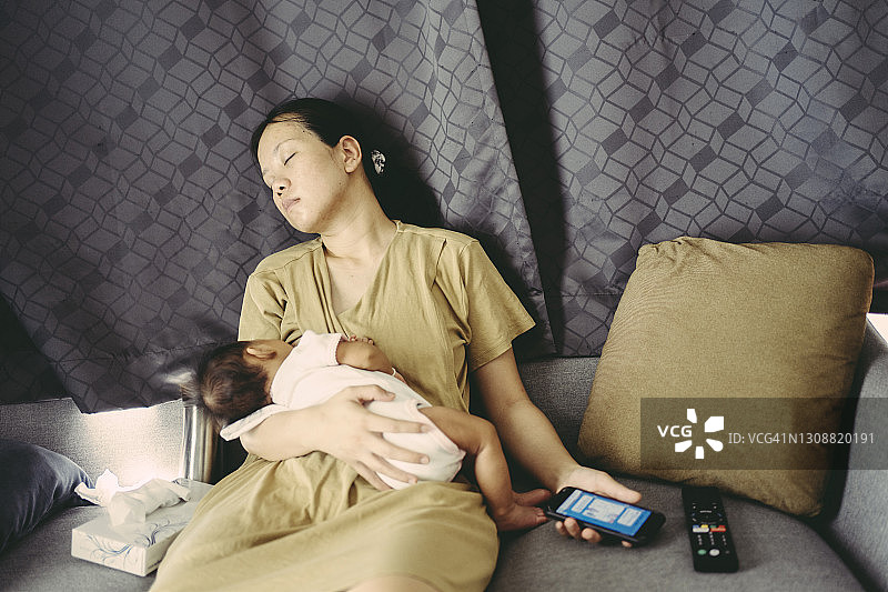 年轻的亚洲母亲在家喂女儿，感到疲惫图片素材