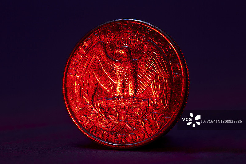 红色照明的美国25美分硬币特写，黑色背景图片素材