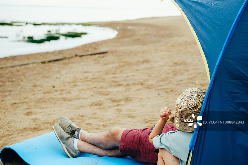 在阴天的夏日或春日，父子在海滩的帐篷里图片素材