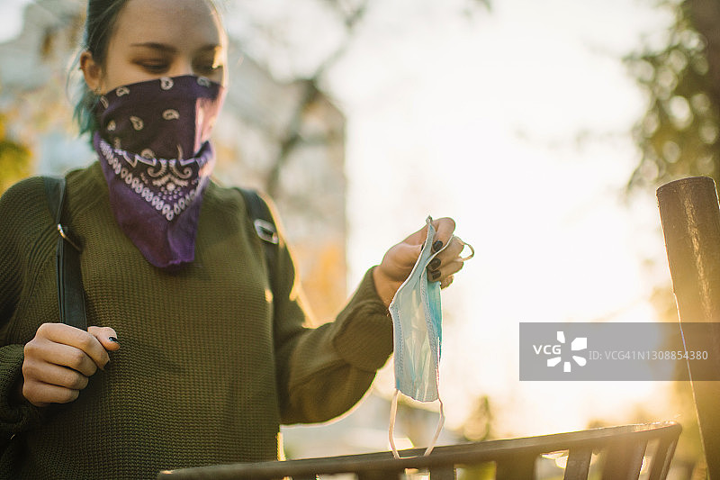 戴着另类面罩的少女将用过的防护口罩扔进垃圾箱图片素材