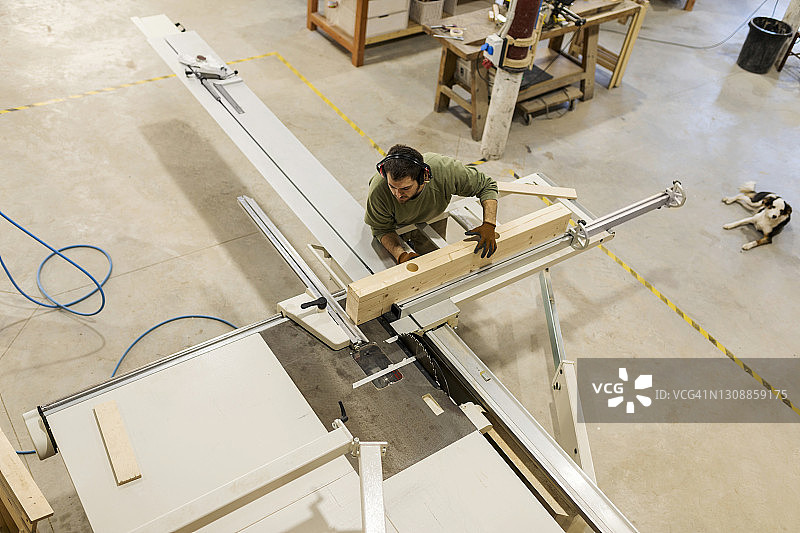 男木匠在车间用台锯加工木材图片素材