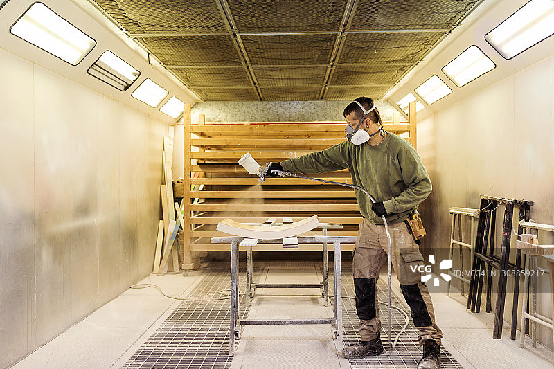 男木匠在喷漆房对木材进行喷漆图片素材
