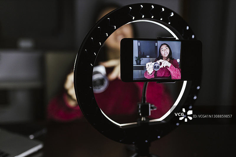 年轻女视频博主在暗房里讲解新相机图片素材