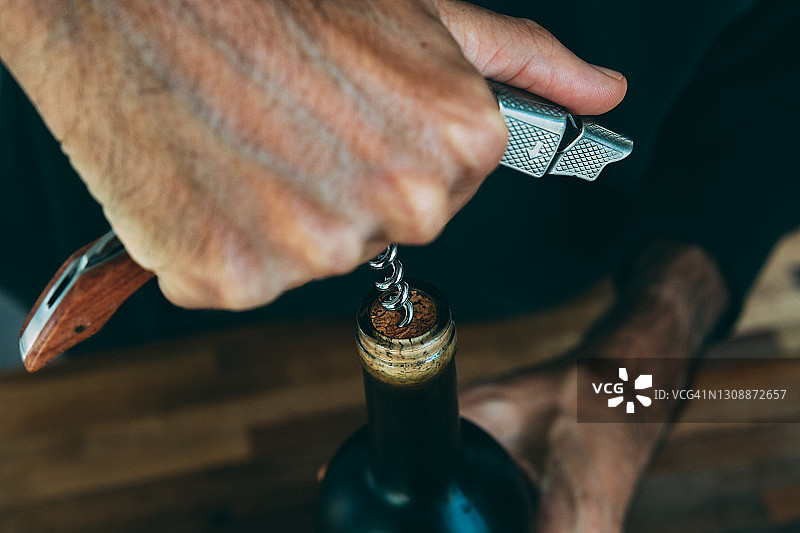 男人用开瓶器打开葡萄酒瓶的手部特写图片素材
