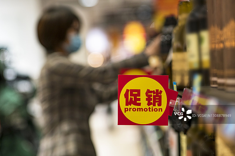 在超市购买红酒的中年亚洲女性，促销标志的特写图片素材