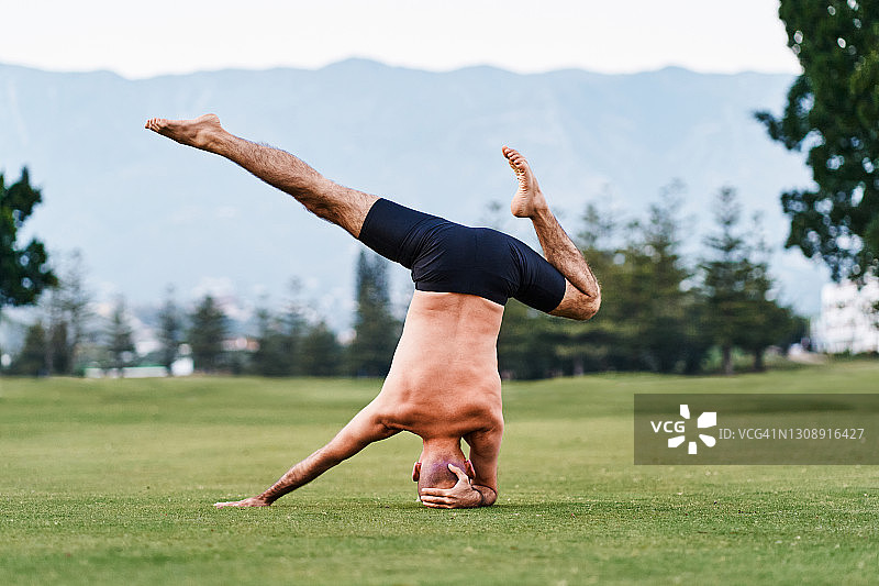 瑜伽男子在草地上倒立图片素材