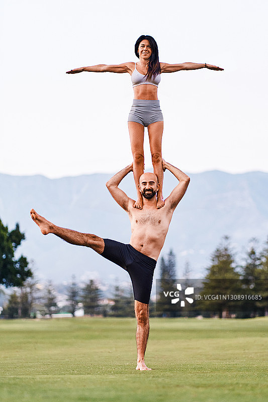 情侣在草地上一起练习双人瑜伽图片素材