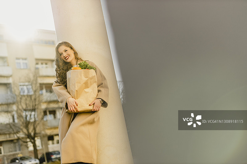 拿着装满食品杂货的纸袋并微笑的年轻女人图片素材