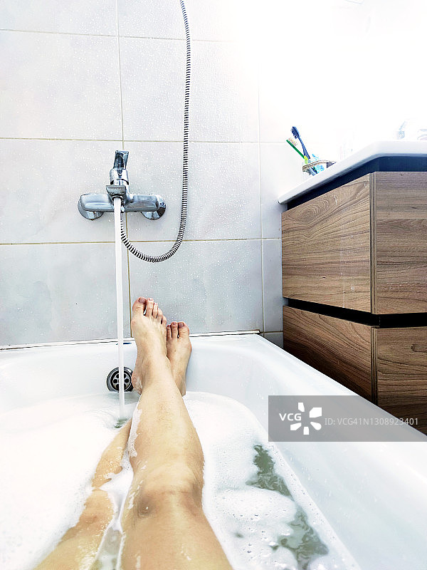 浴室里在水流下享受泡沫浴的美丽女人的脚图片素材