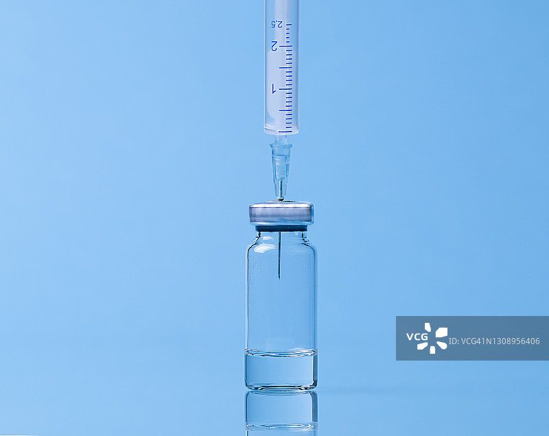 疫苗瓶特写，反射面上的针头和注射器图片素材