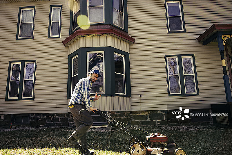 男人在修剪草坪时做出和平手势图片素材