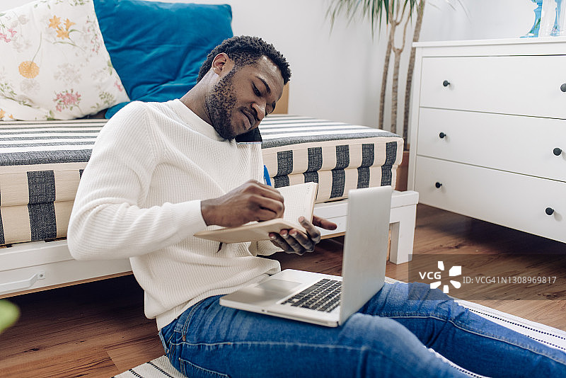 年轻的非裔美国男子在家工作时正在打电话图片素材