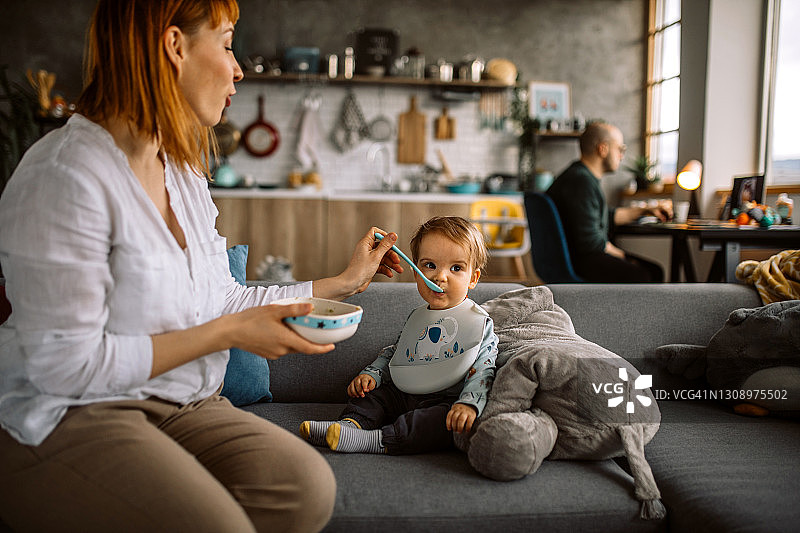 年轻母亲用勺子喂她的男婴图片素材
