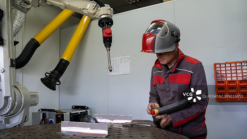 工程师在工厂设置自动机器人手臂，数字化制造运营。图片素材