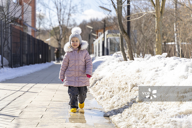 在春天水坑里跳跃的白人小女孩图片素材