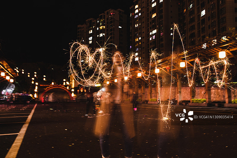 用烟花棒绘制心形图案的长曝光图片素材