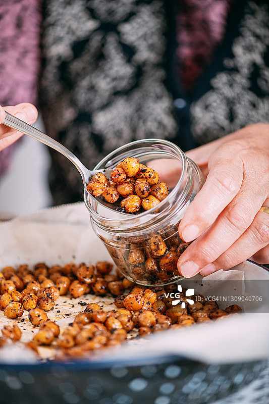 她将准备好的香辣鹰嘴豆倒入罐中图片素材